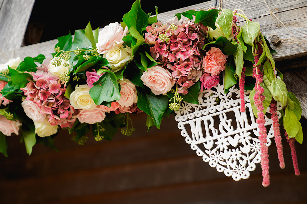 The wooden beams of the entrance to this Cheshire barn were decorated with garlands of pretty pink flowers 
