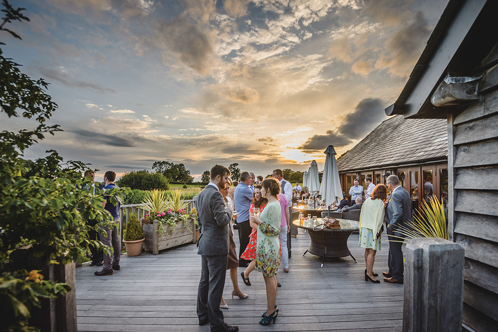 Wedding guests enjoying mingling in the sunset at this summer wedding at Sandhole Oak Barn