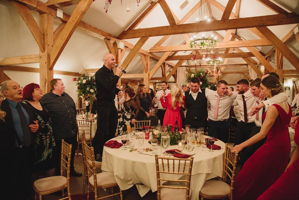 The wedding guests enjoy a sing-song at this winter wedding at Sandhole Oak Barn